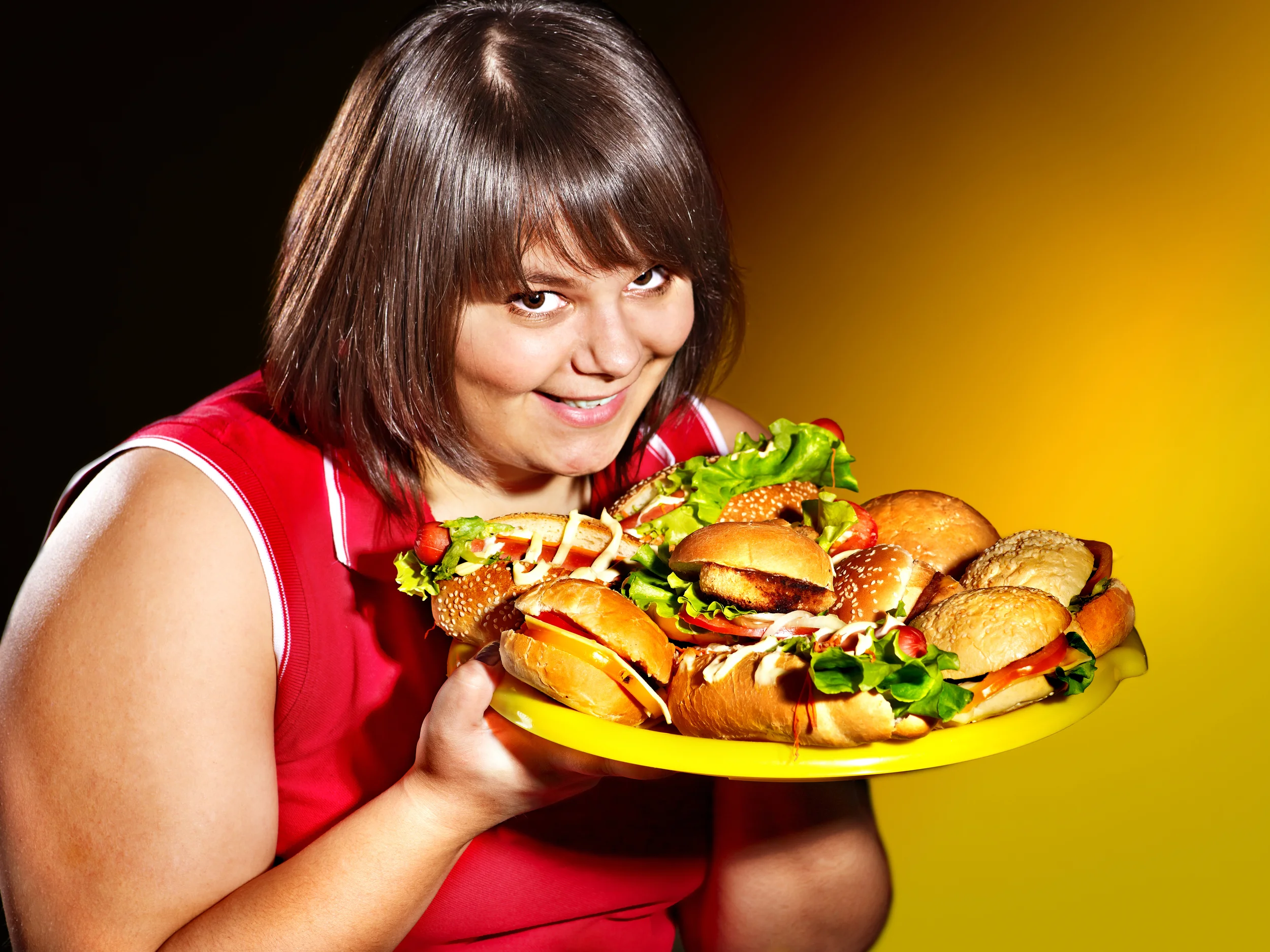 Overweight woman holding hamburger