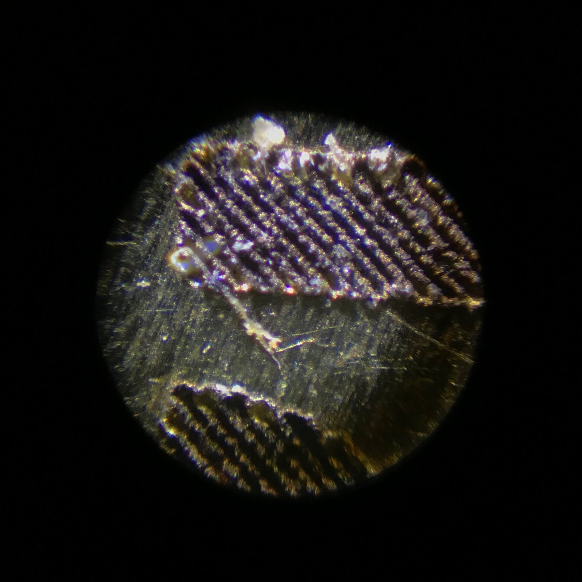 a trial laser dial engraving under magnification showing less than ideal ablation of the base material.