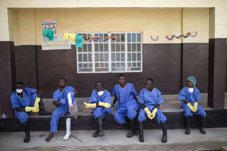 © REUTERS/Baz Ratner Health workers rest outside a quarantine zone at a Red Cross facility in the town of Koidu, Kono district in Eastern Sierra Leone December 19, 2014.
