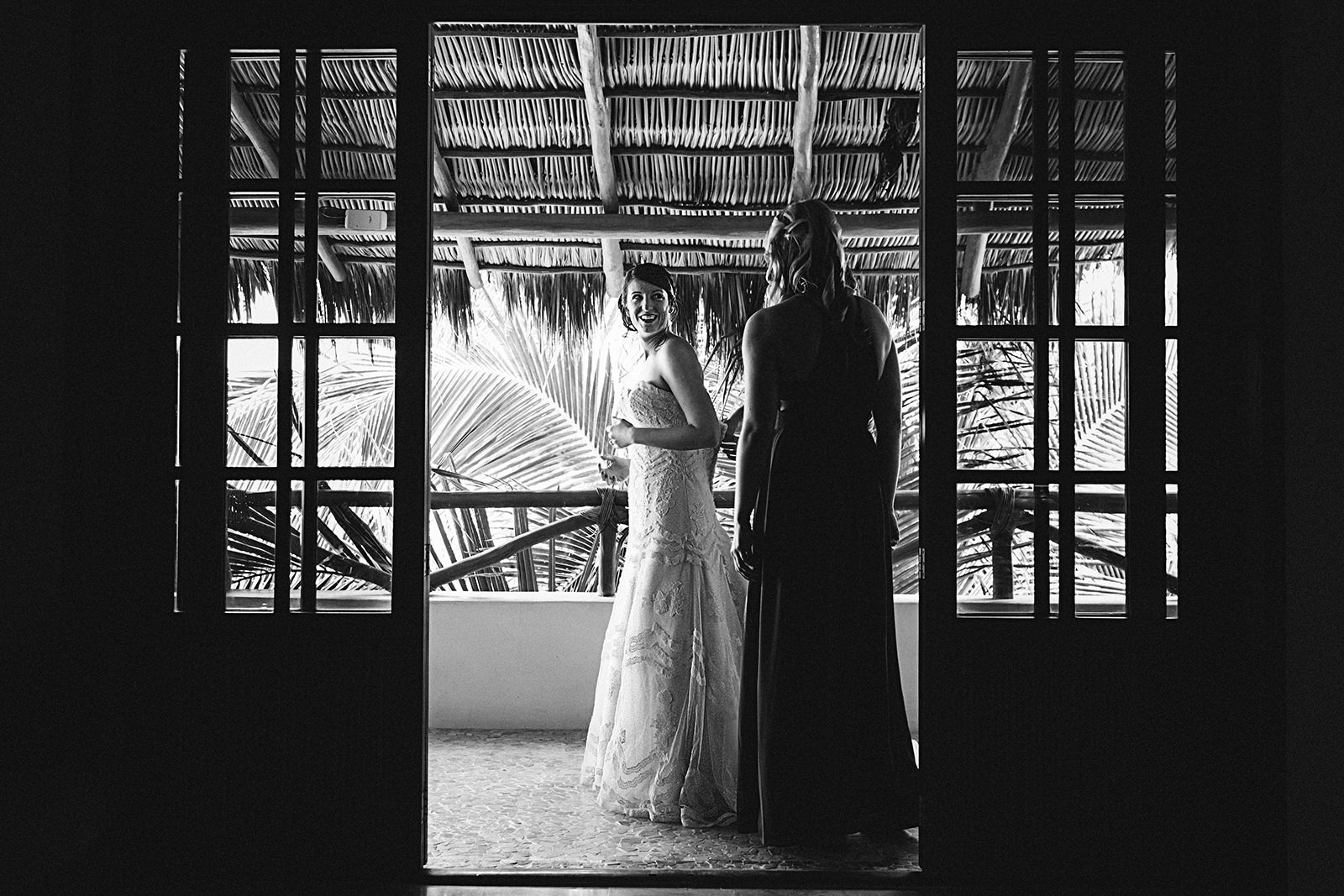 Bridesmaids help the bride with her dress on the room balcony at Playa Fiesta Mexico