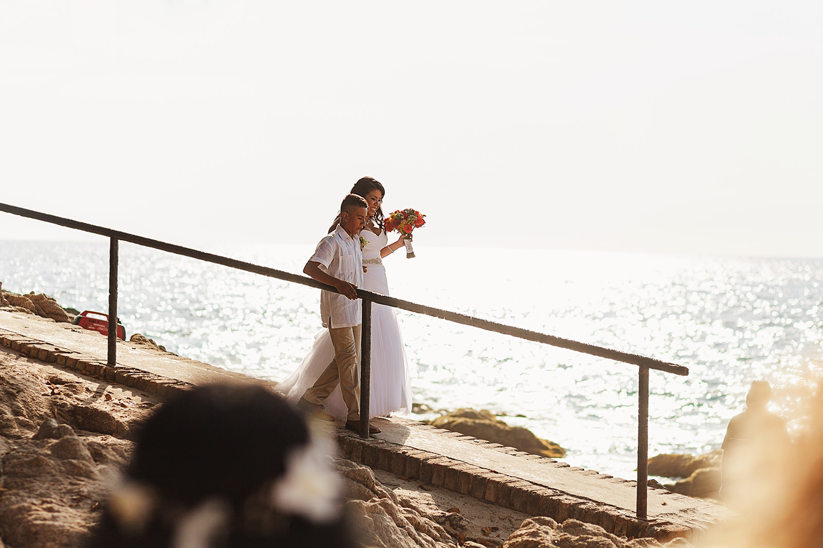 Bride and her son walking down a ramp to get to the beach ceremony
