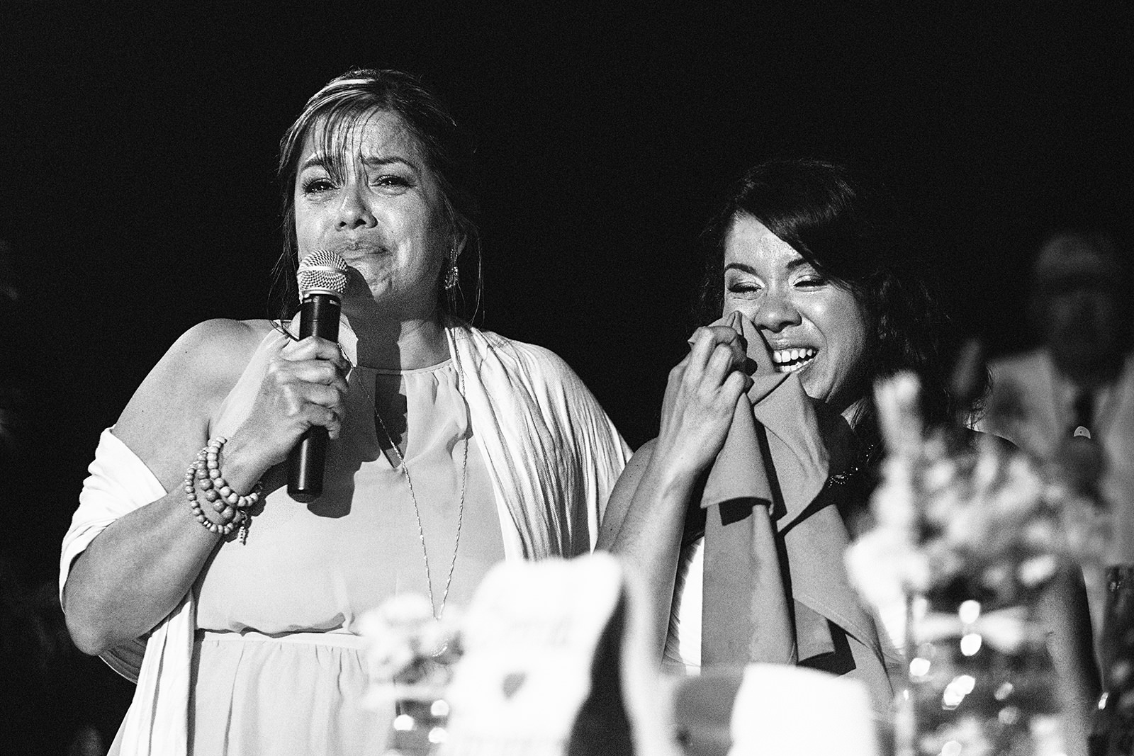 Bride's mom crying during speech and bride laughing while whipping tear