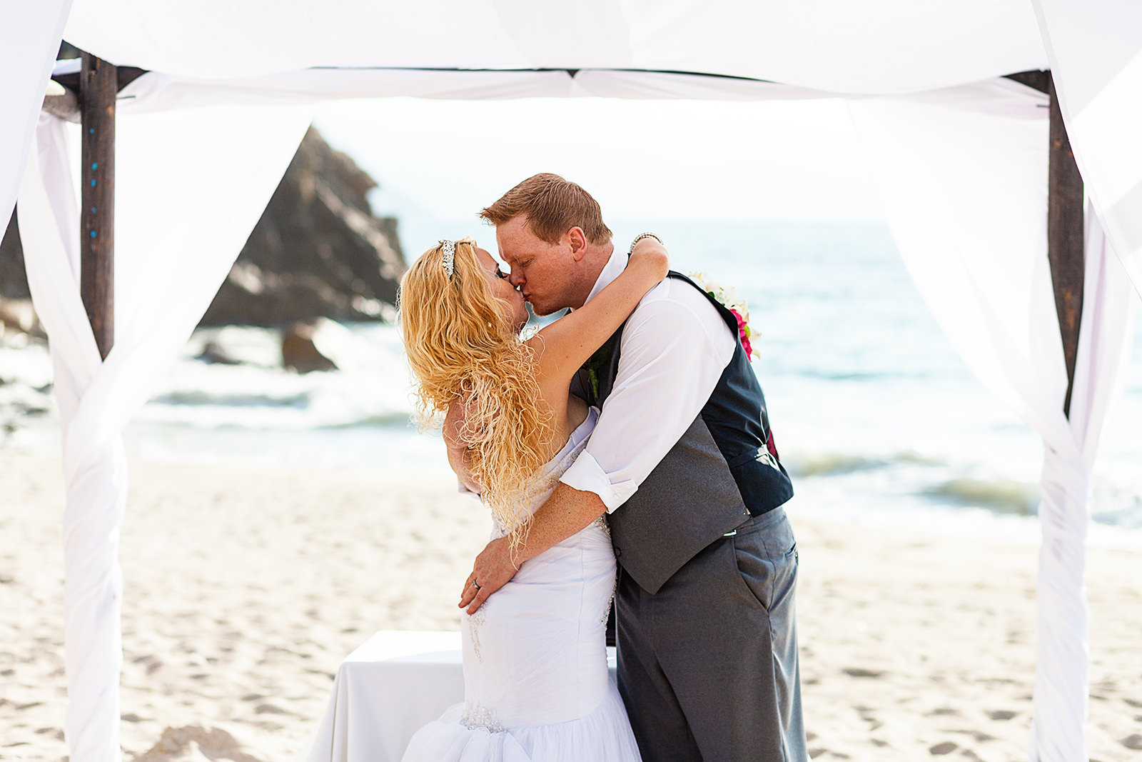 wedding couple's first kiss on their beach ceremony under a chuppahp