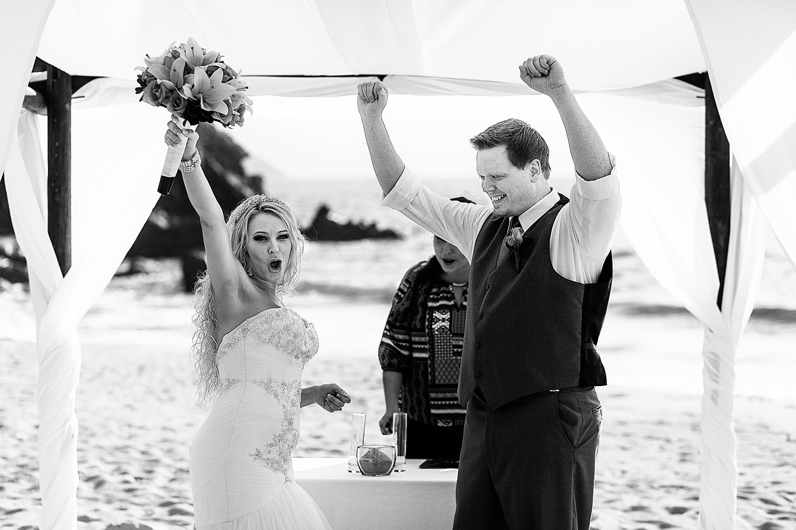 Wedding couple celebrates at ceremony on beach, black and white moment