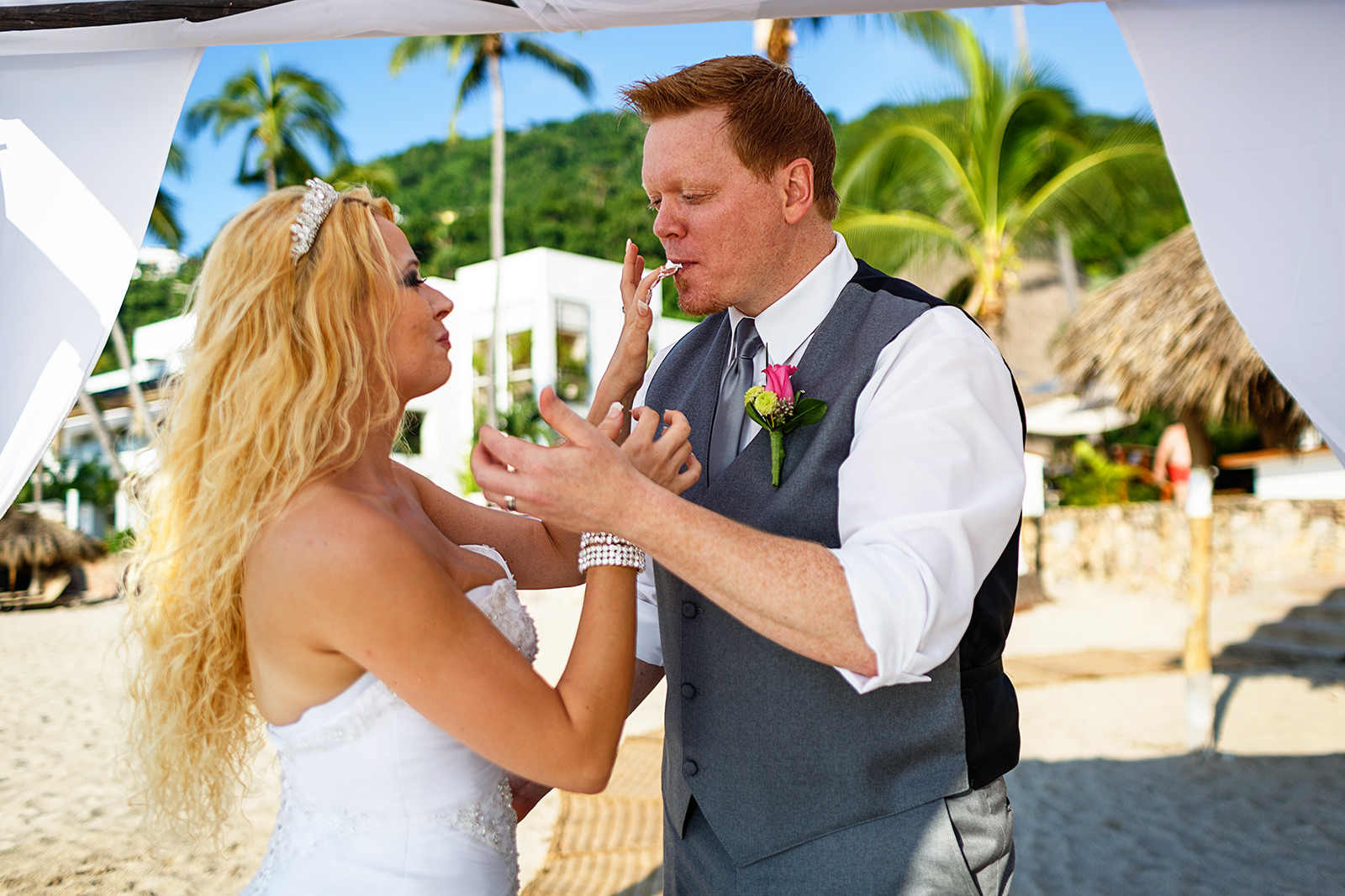 bride and groom feed cake at each other after ceremony on the beach