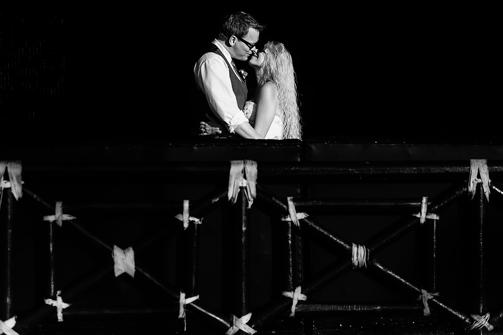 black and white kiss of wedding couple against black background