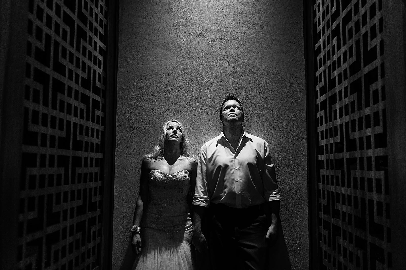 bride and groom looking up standing against a wall