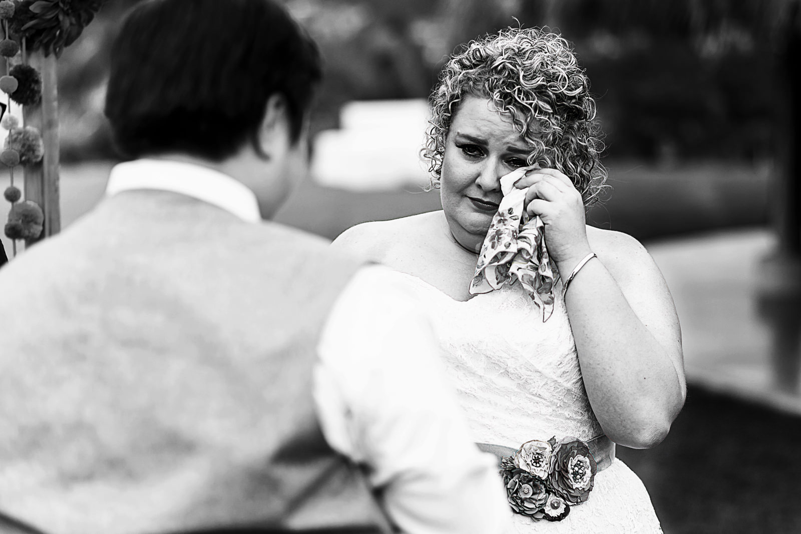 Bride wiping tear with handkerchief at wedding ceremony 