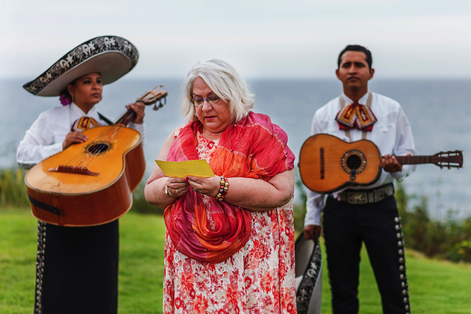 wedding guest reading a few words for ceremony between two mariachi players in background