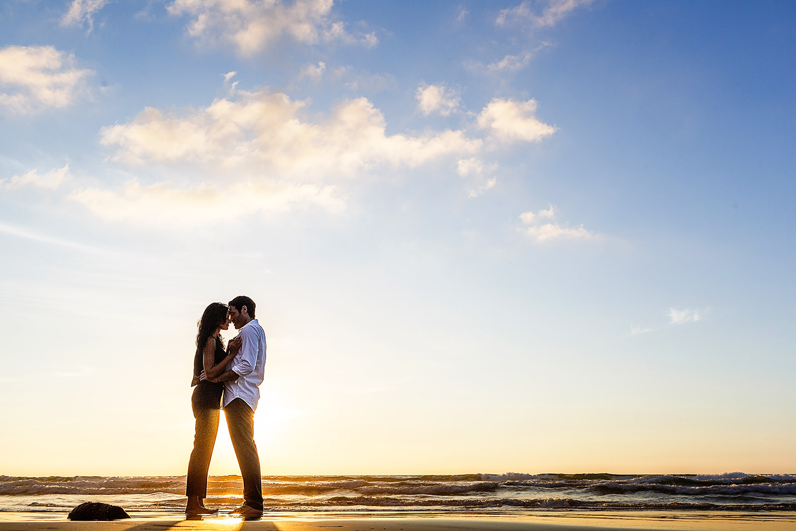 Couple standing and leaning their faces into each other during sunset