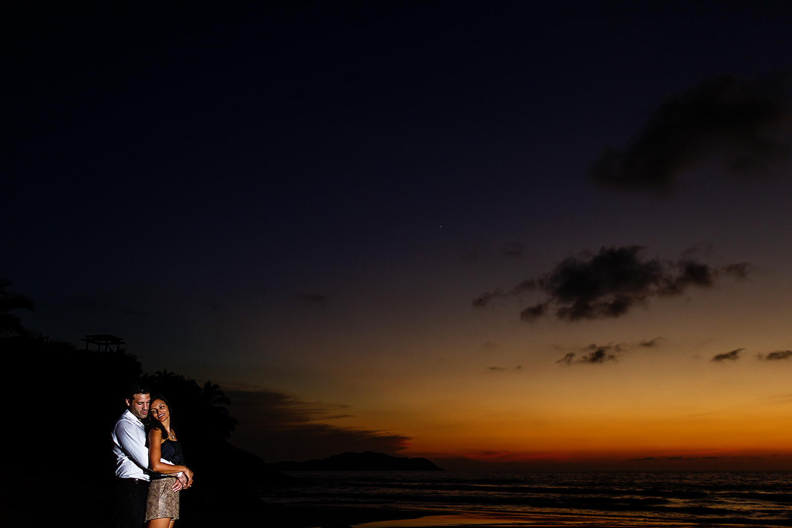 Couple standing on the beach under dramatic