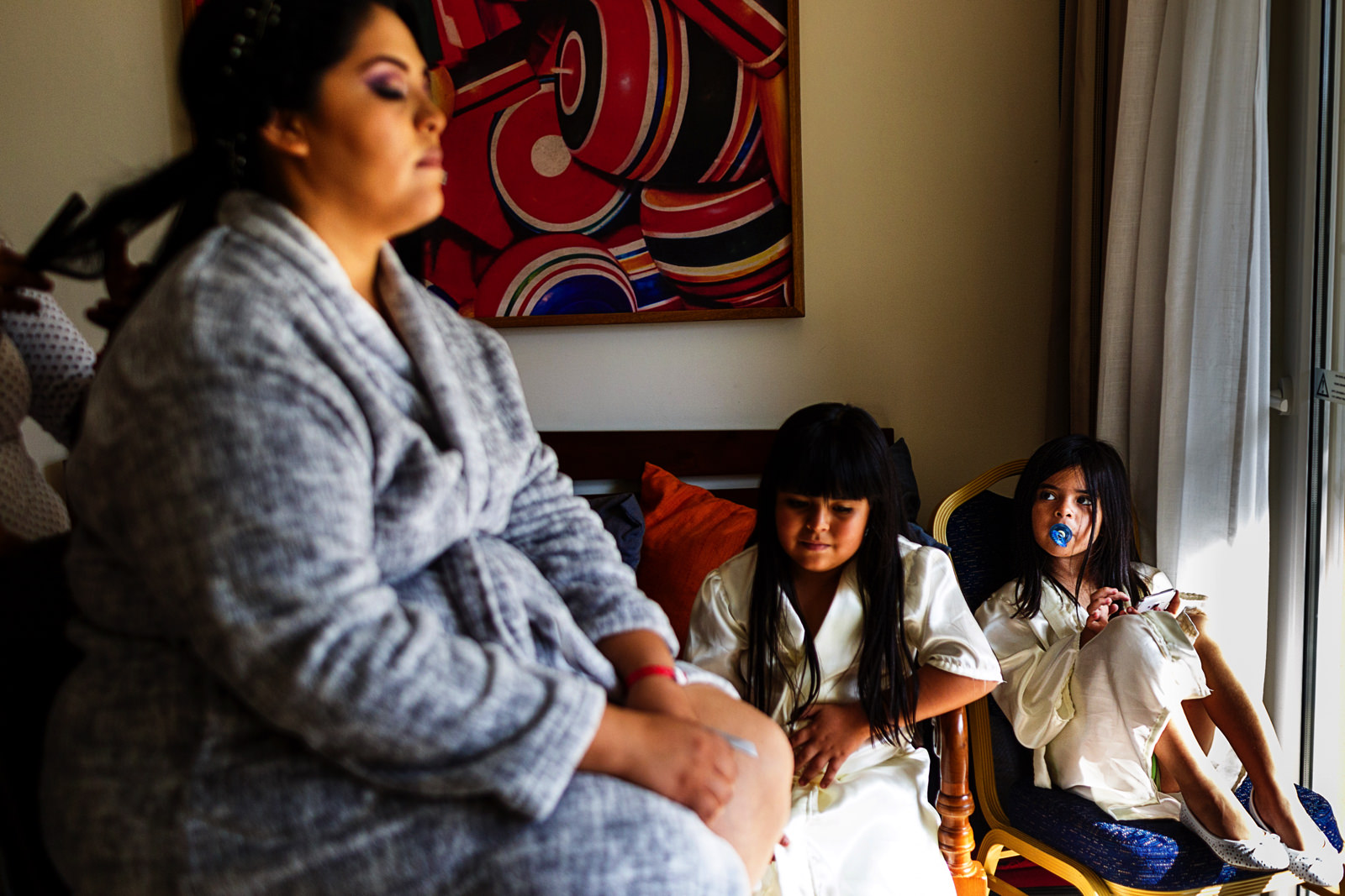 Bride getting her hair done before the ceremony right next to her daughters 