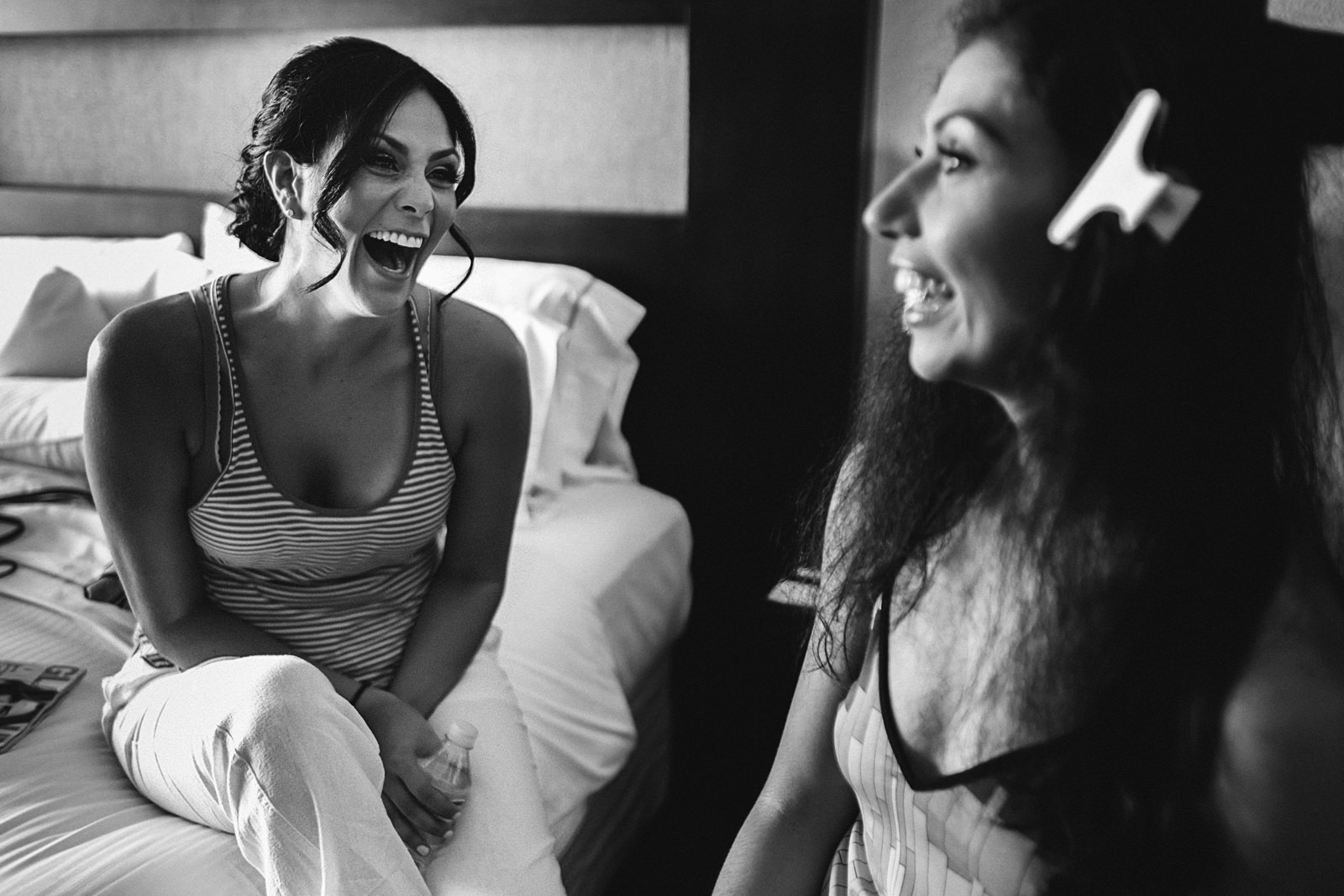 Bridesmaid laughing with bride during getting ready