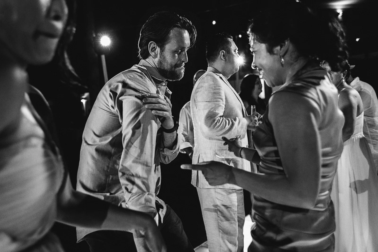 Mixed bride and groom guests dancing together at wedding reception party