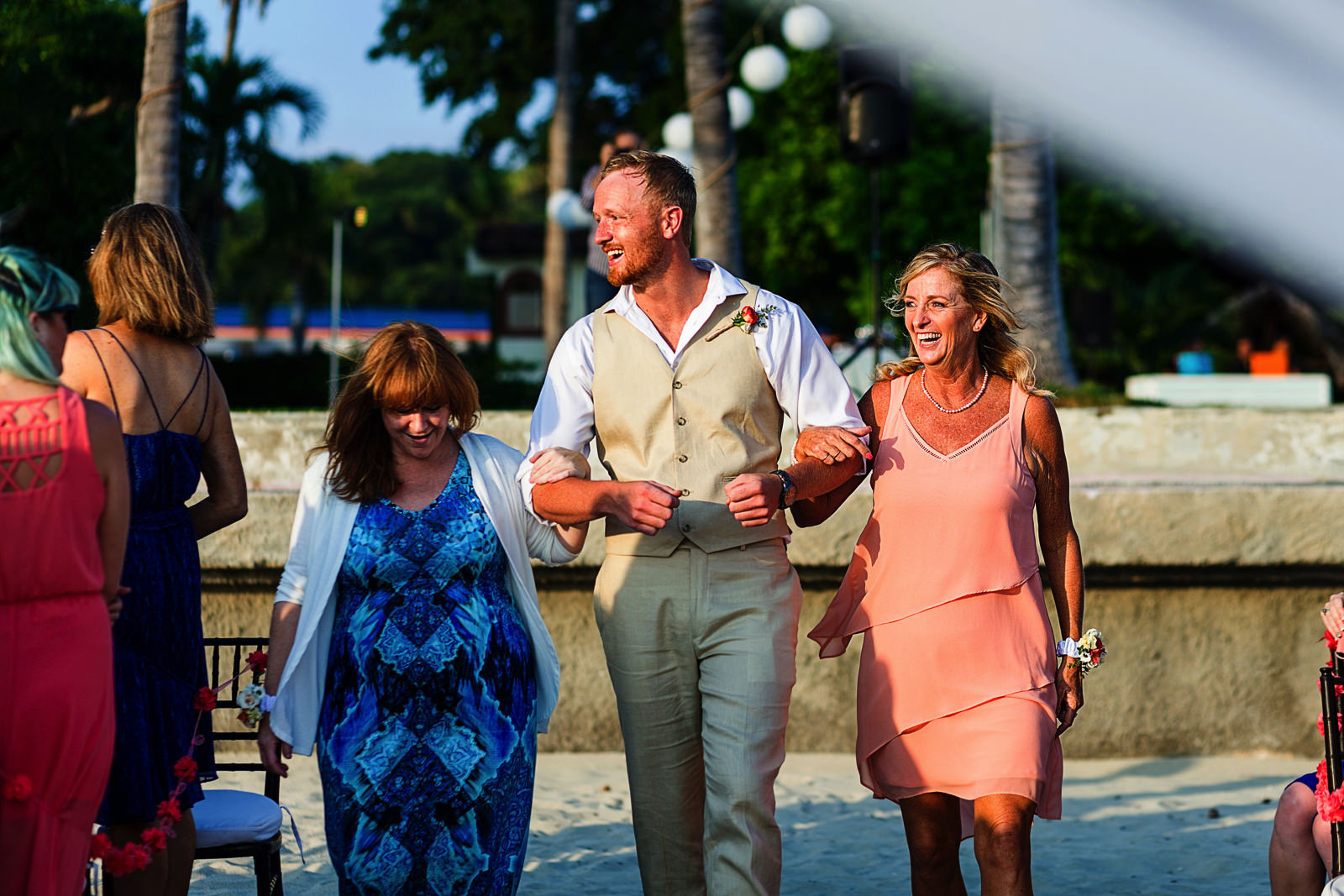 Groom walking down the aisle with both moms