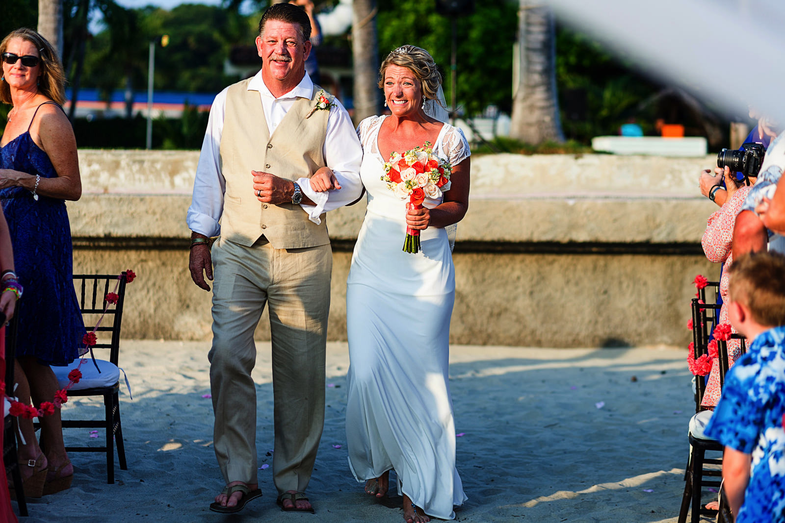 Dad and bride walking down the aisle, bride reacts with big smile to guests