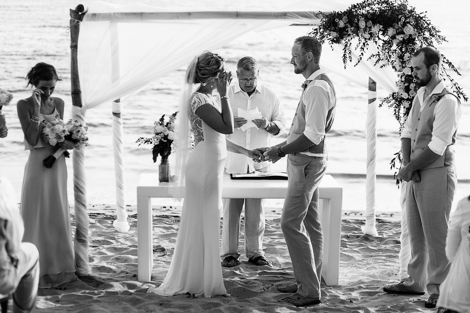 Bride and sister crying during wedding ceremony on the beach