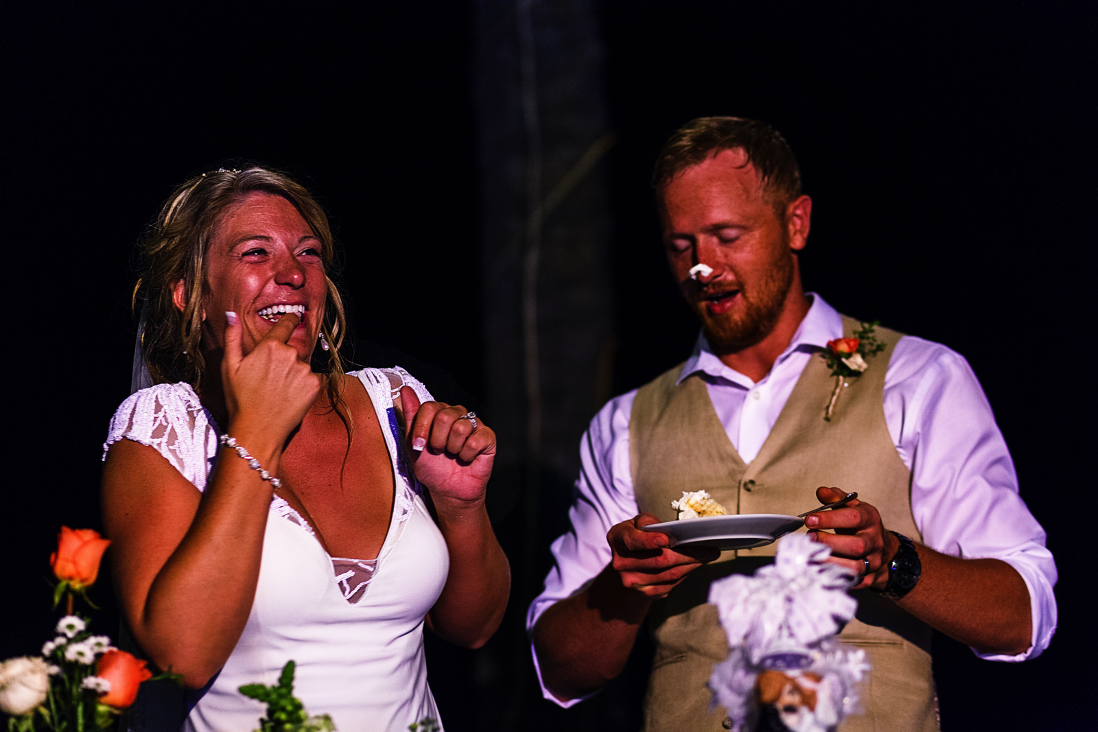 Bride laughing after putting some wedding cake on the groom's nose