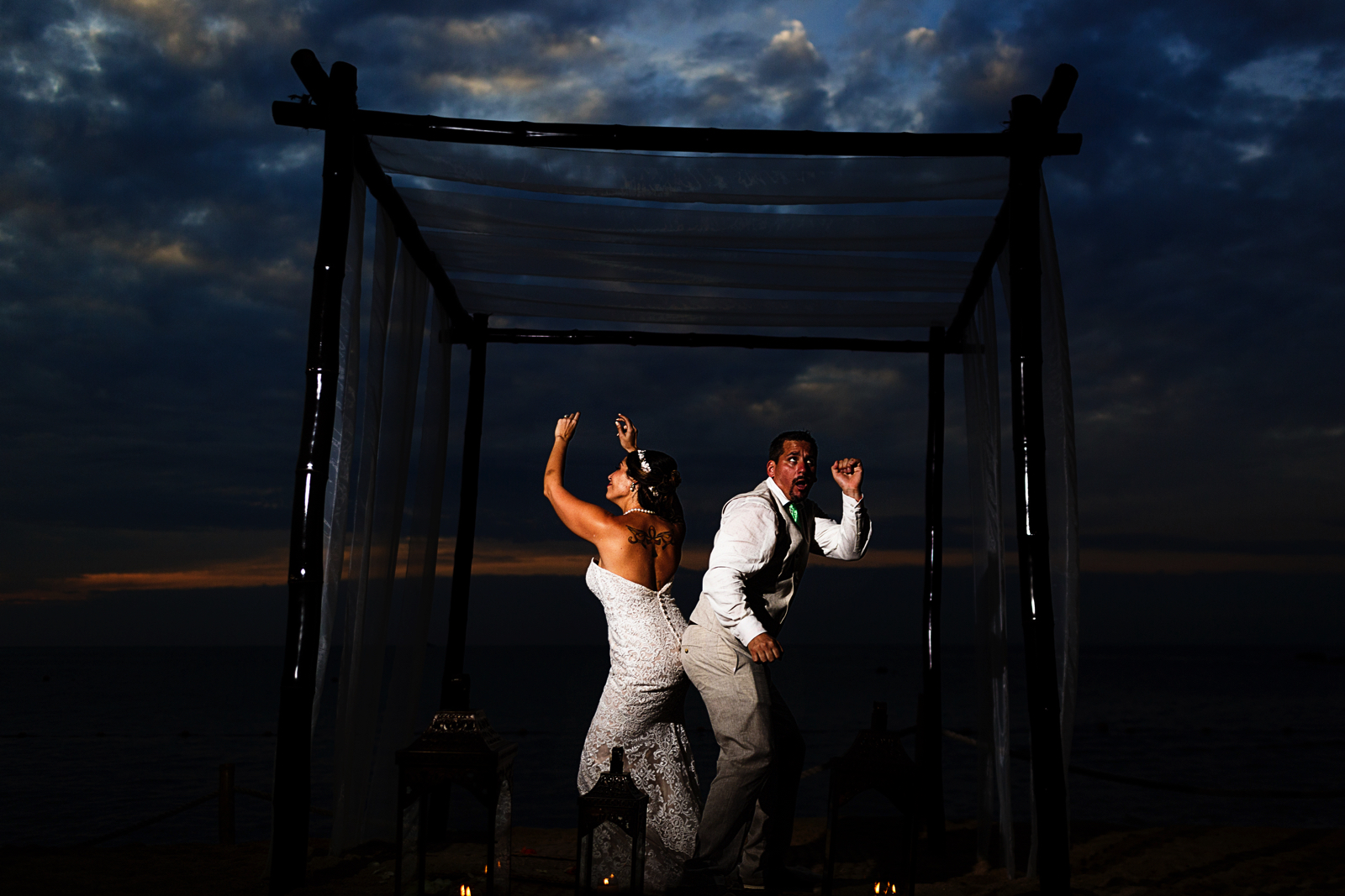 Portrait of the couple dancing under the chuppah at sunset on the beach