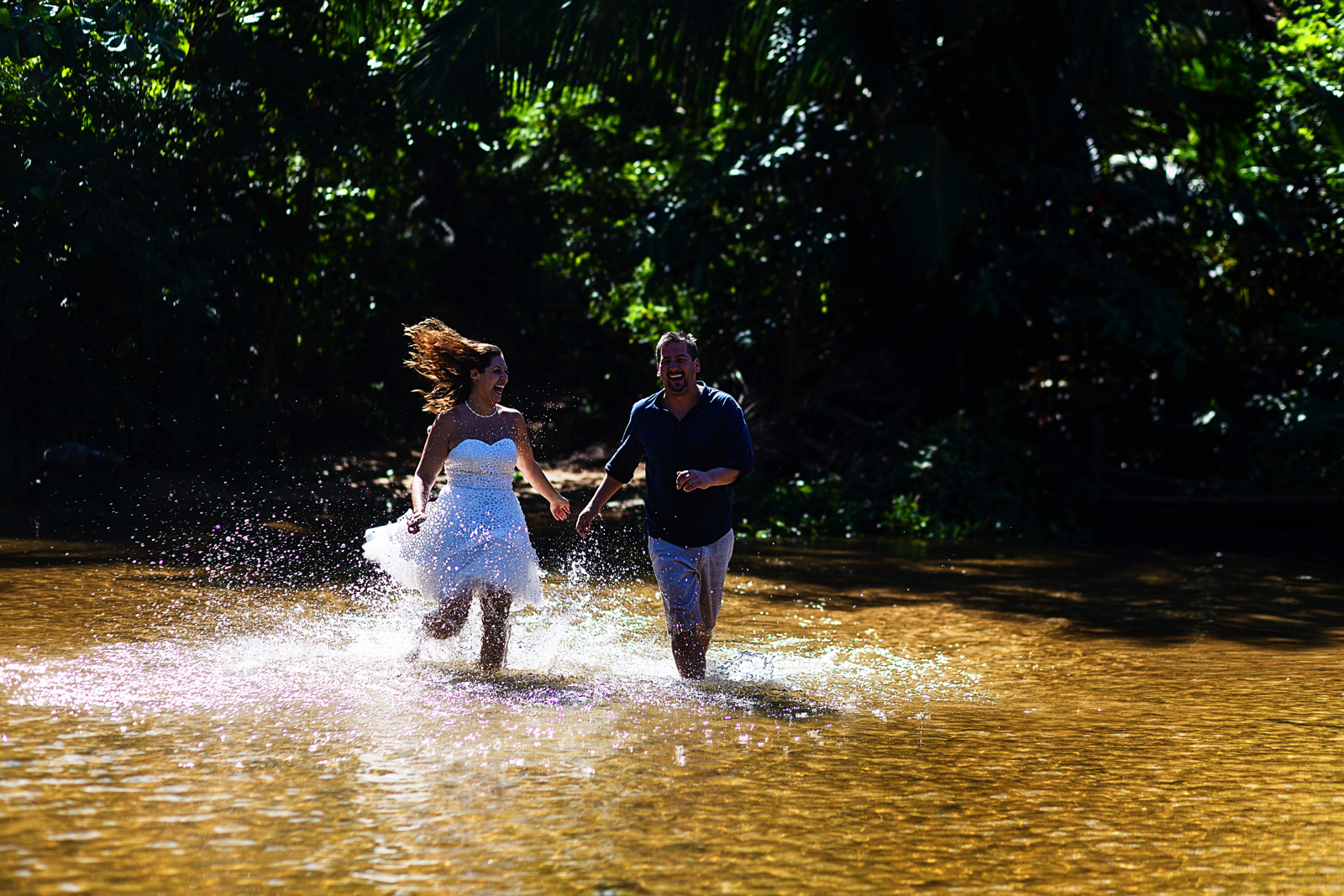 Groom and bride running in the river during their trash-the-dress photo session