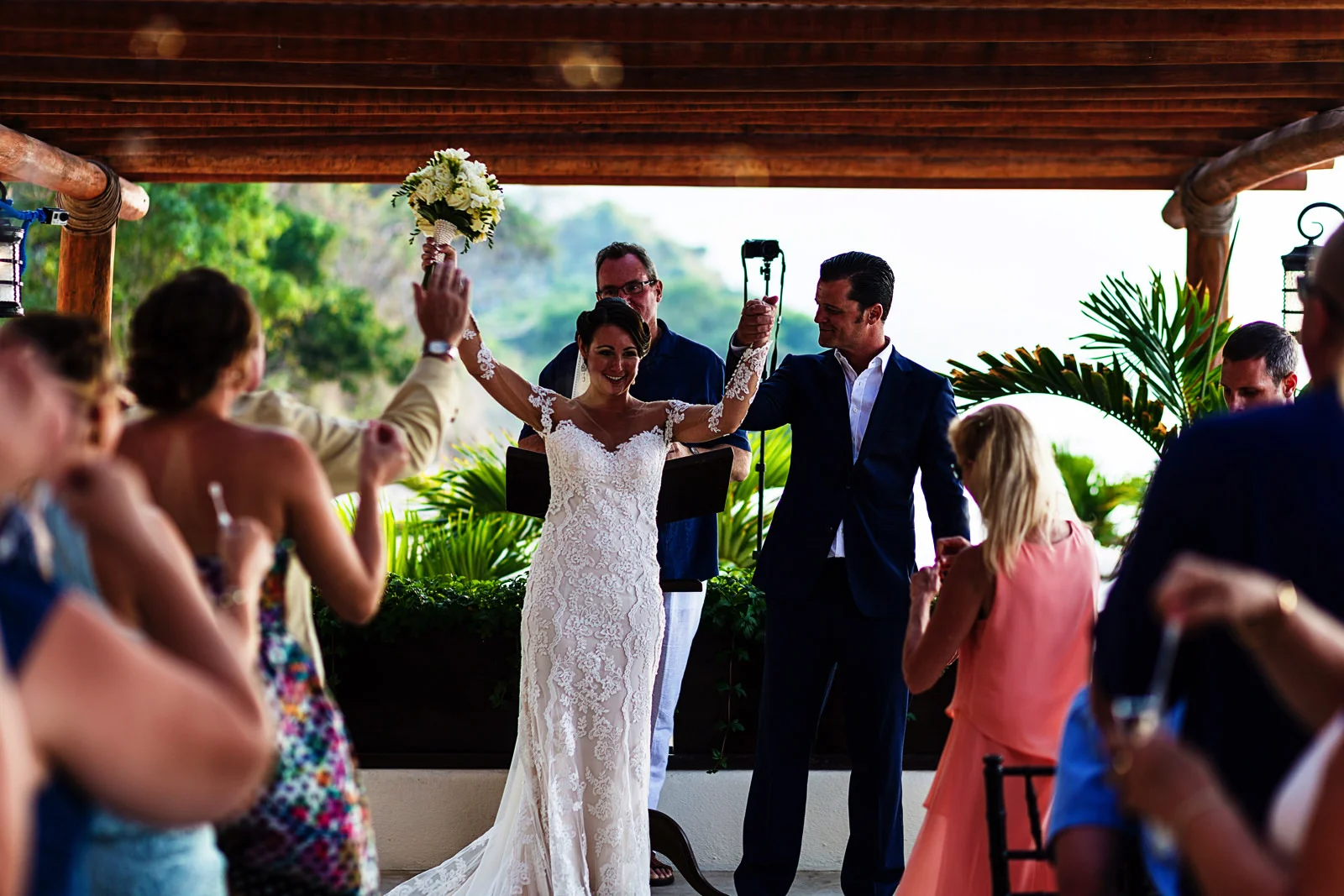 Groom and bride raising their arms as the wedding ceremony ends