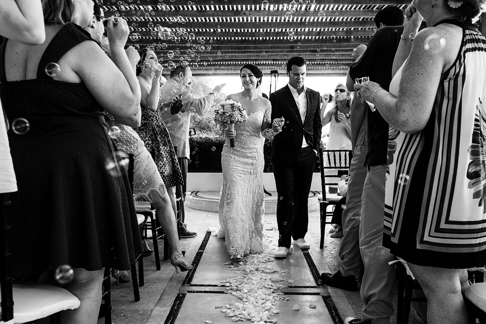 Groom and bride walking out the ceremony whilst guests blow bubbles
