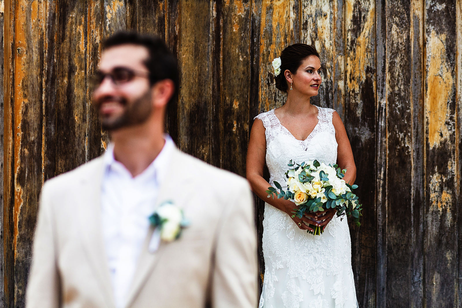 Portrait of a groom and bride on a door outside a tequila factory, groom in fore ground out of focus