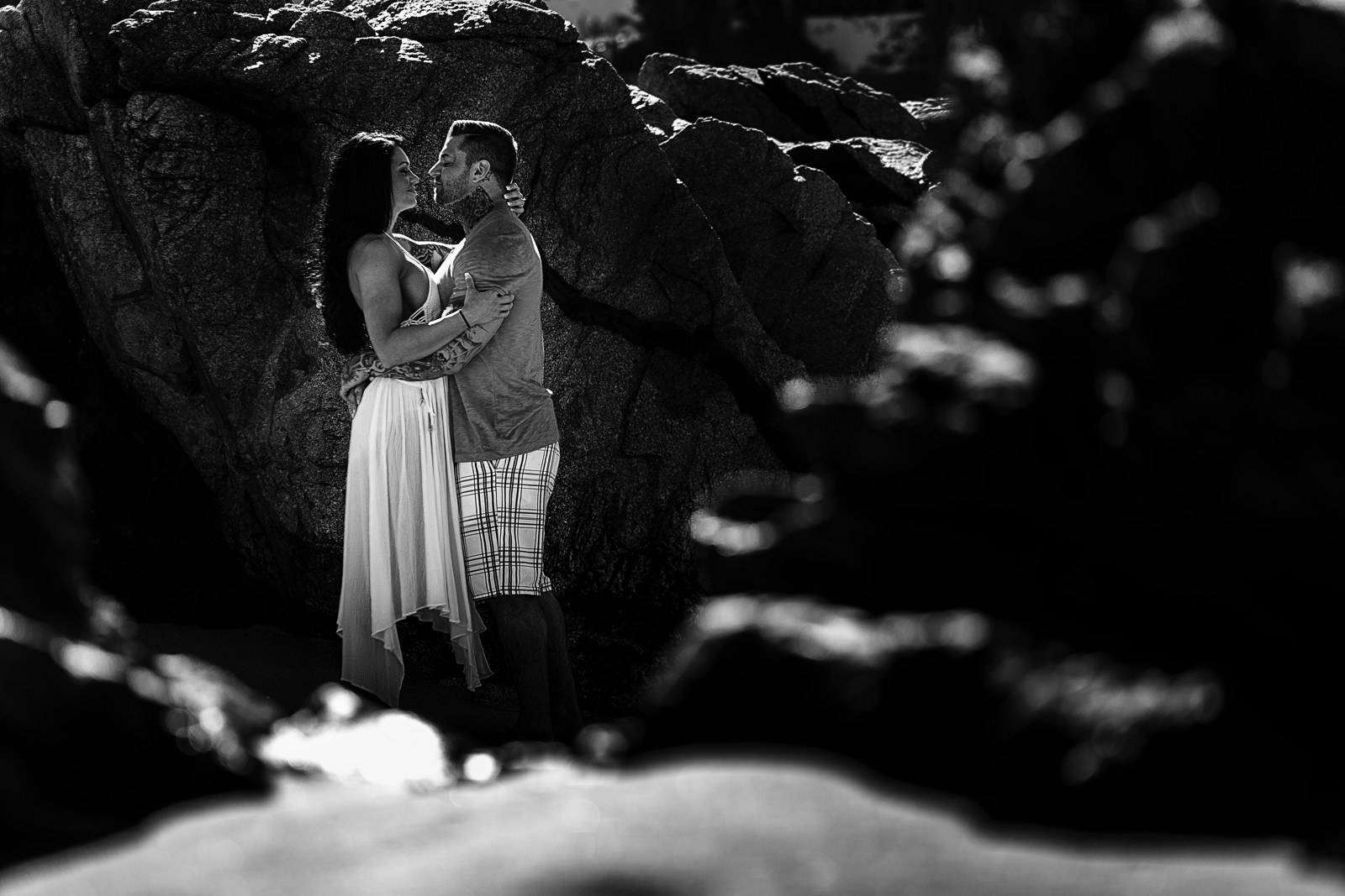 Couple about to kiss hidden in the rocks of Conchas Chinas beach
