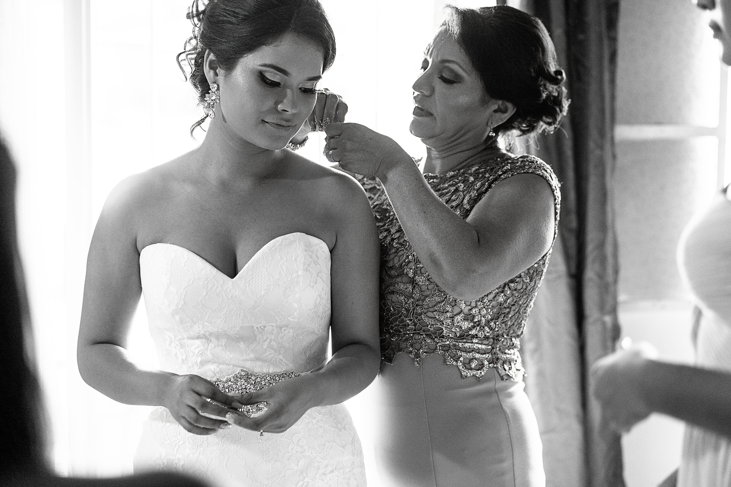 Mamá de la novia poniéndole los aretes a la novia durante los preparativos