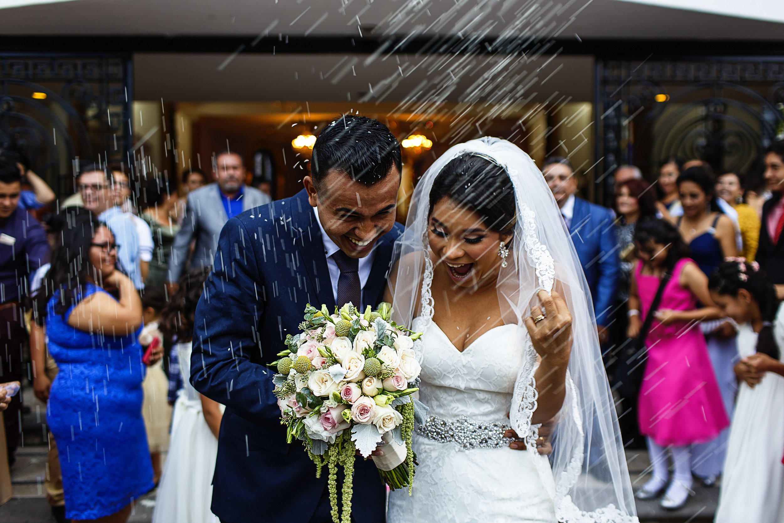 La feliz pareja reacciona a la lluvia de arroz al terminar su ceremonia religiosa de boda