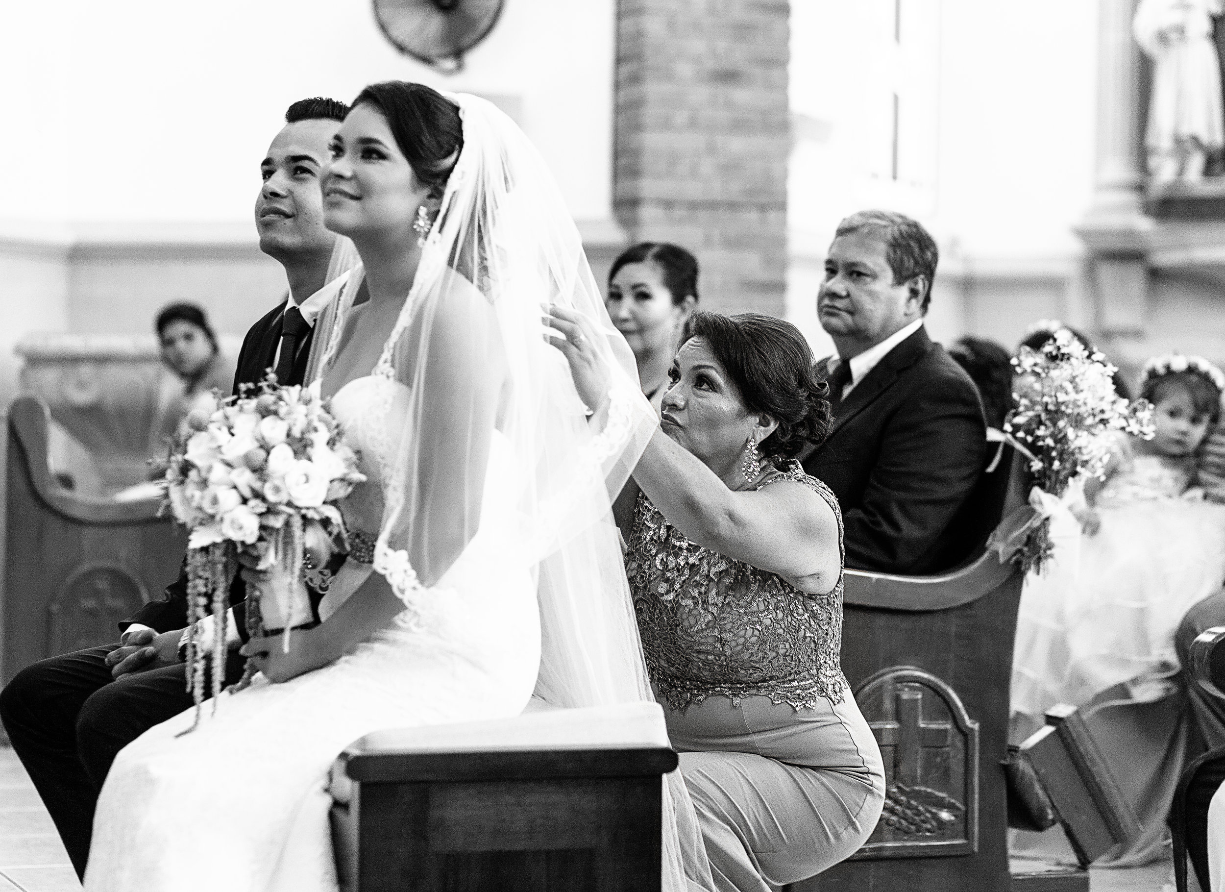 Madre de la novia reajustando el velo durante la ceremonia religiosa de la boda