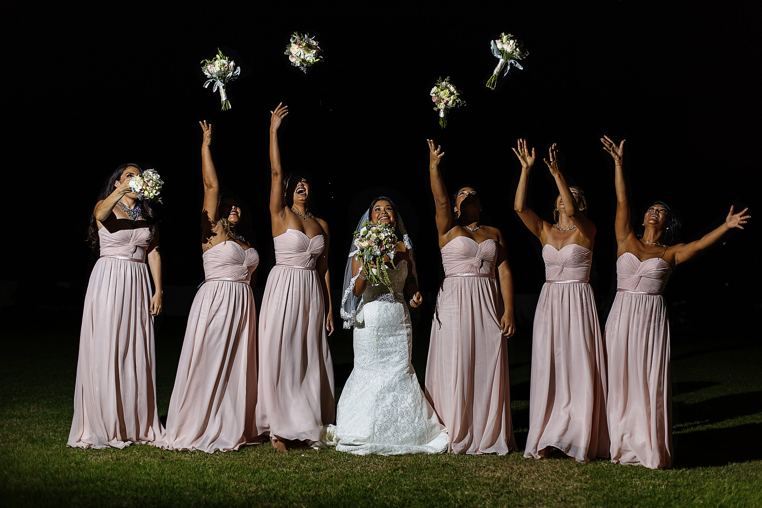Retrato de la novia con sus damas lanzando los ramos al cielo