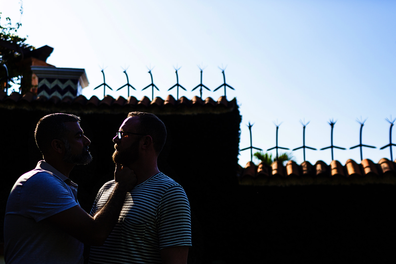 Silhouette of a couple with light against a dark wall outside Casa Muni