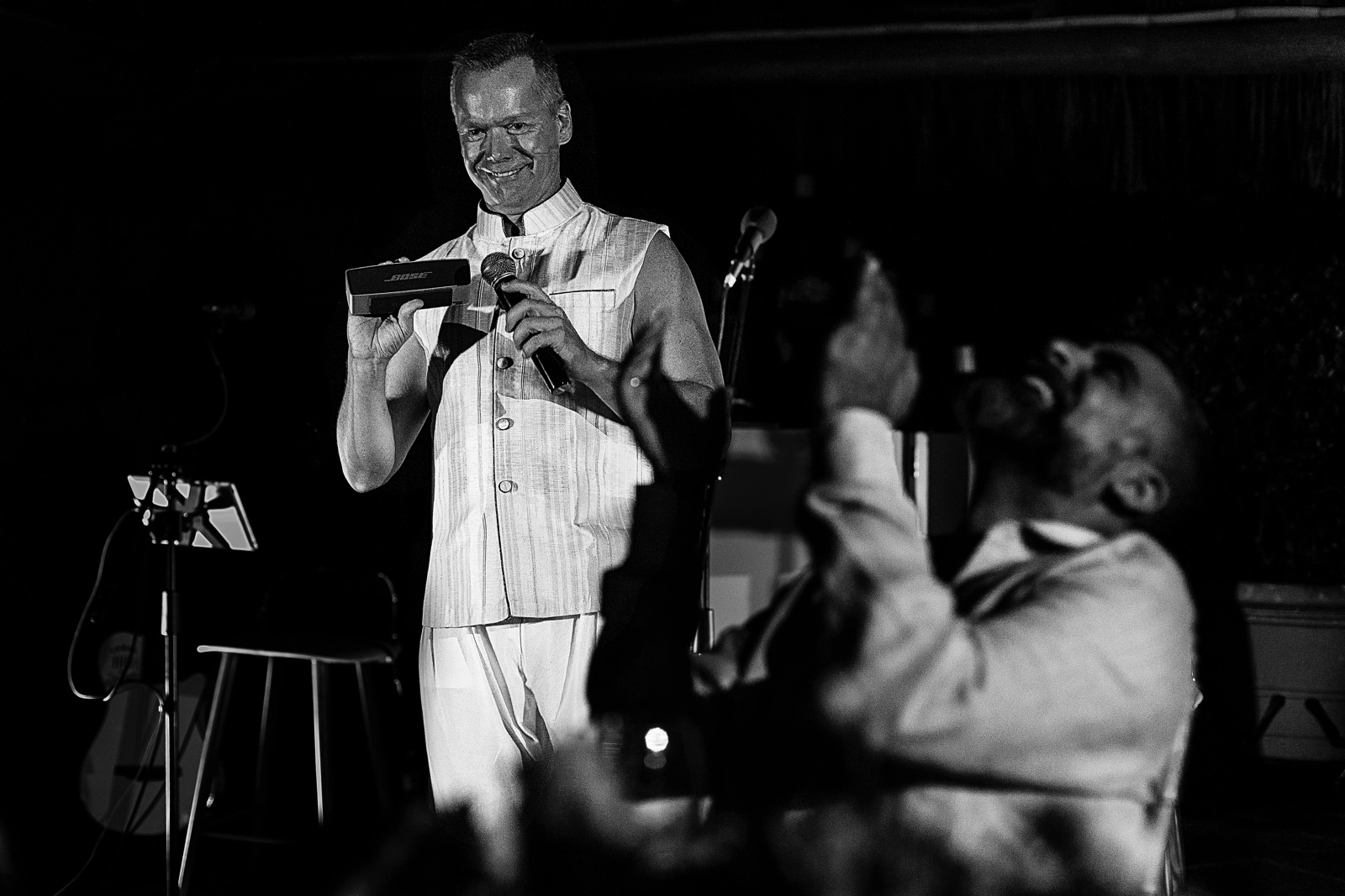Best man holds a boombox against the microphone on his speech, the groom reacts laughing