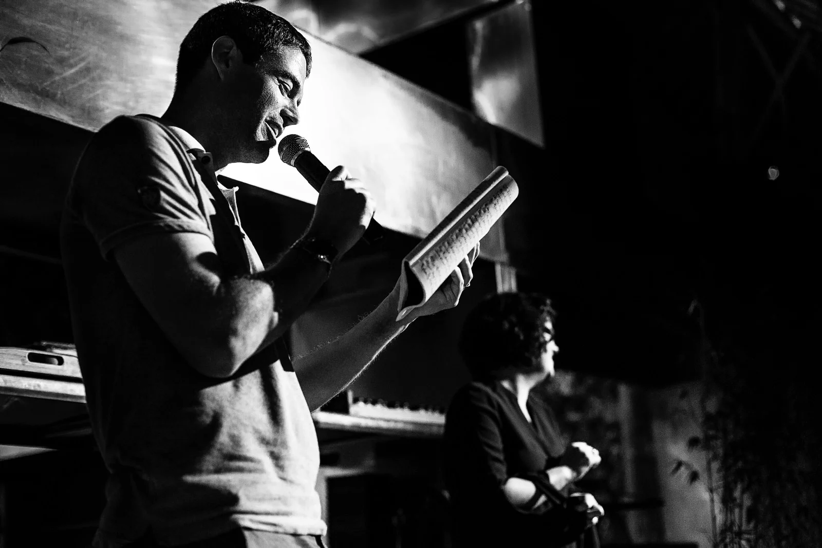 Wedding guest talking over the mic and holding a notebook during the rehearsal dinner