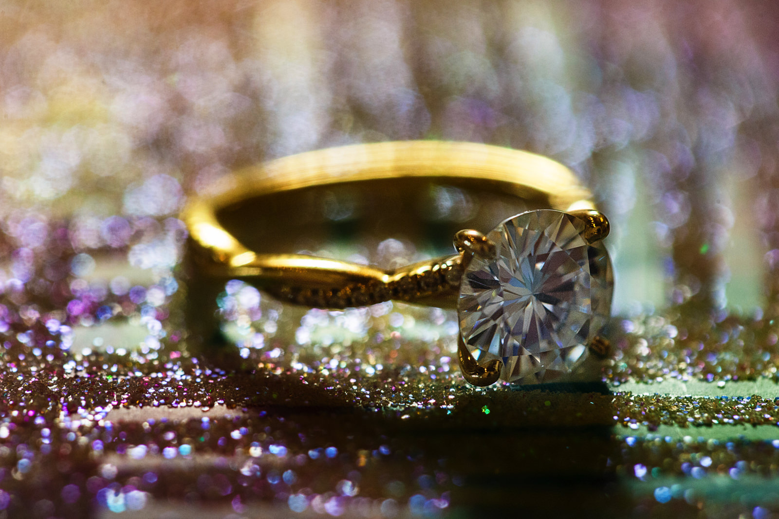 Close up of an engagement ring over a sparkling surface