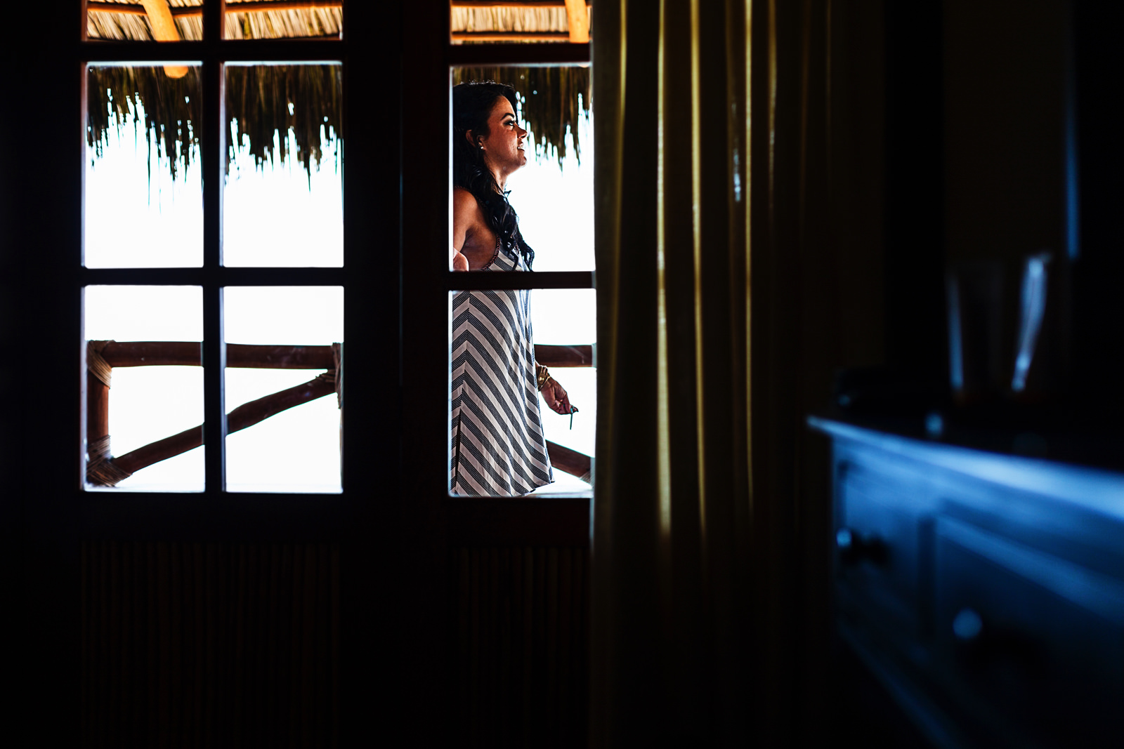 A girl can be seen through a window having a cigarette break out in the balcony of the room where all girls are getting ready for the wedding