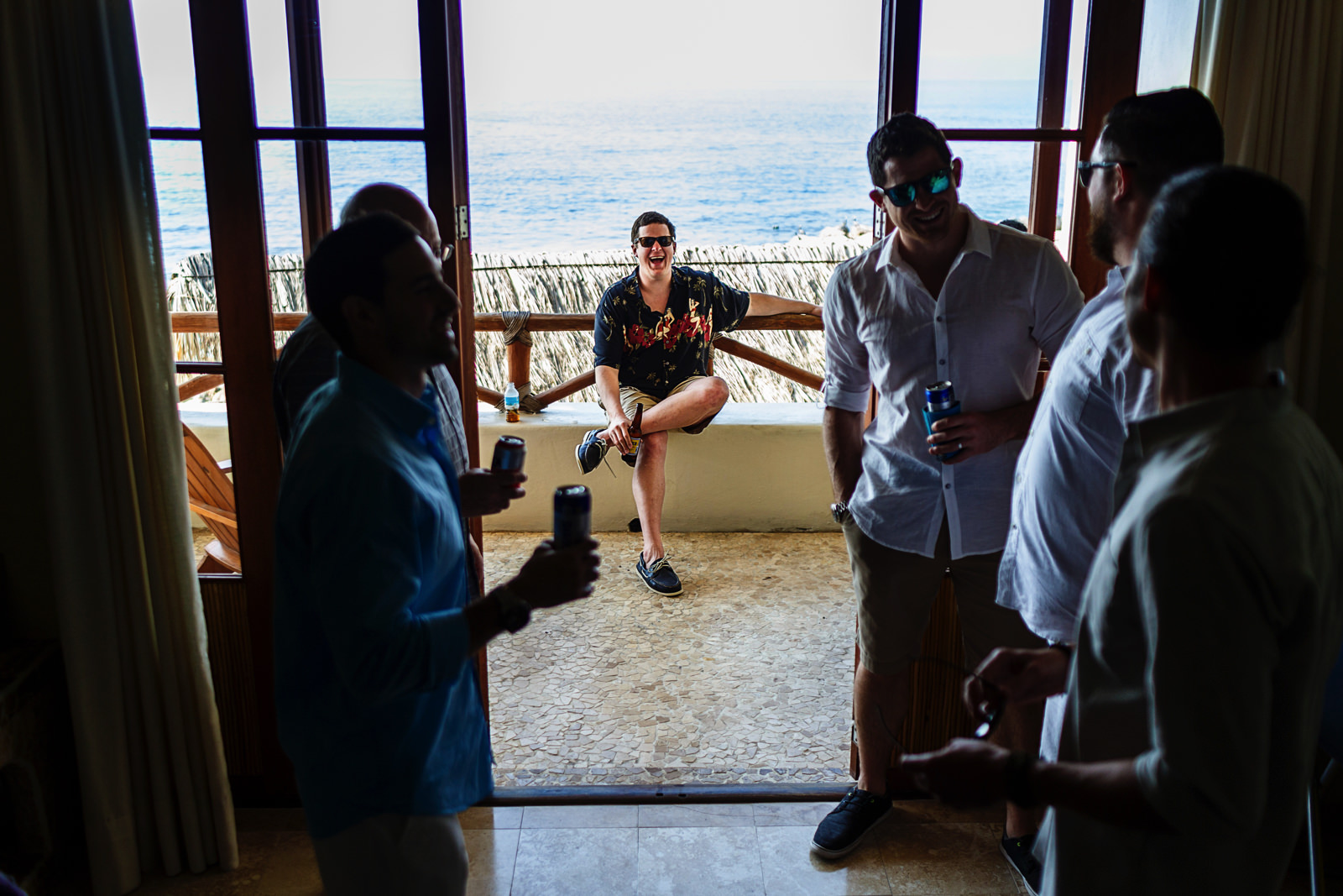 Guys room having beers and sharing laughs before the destination wedding ceremony