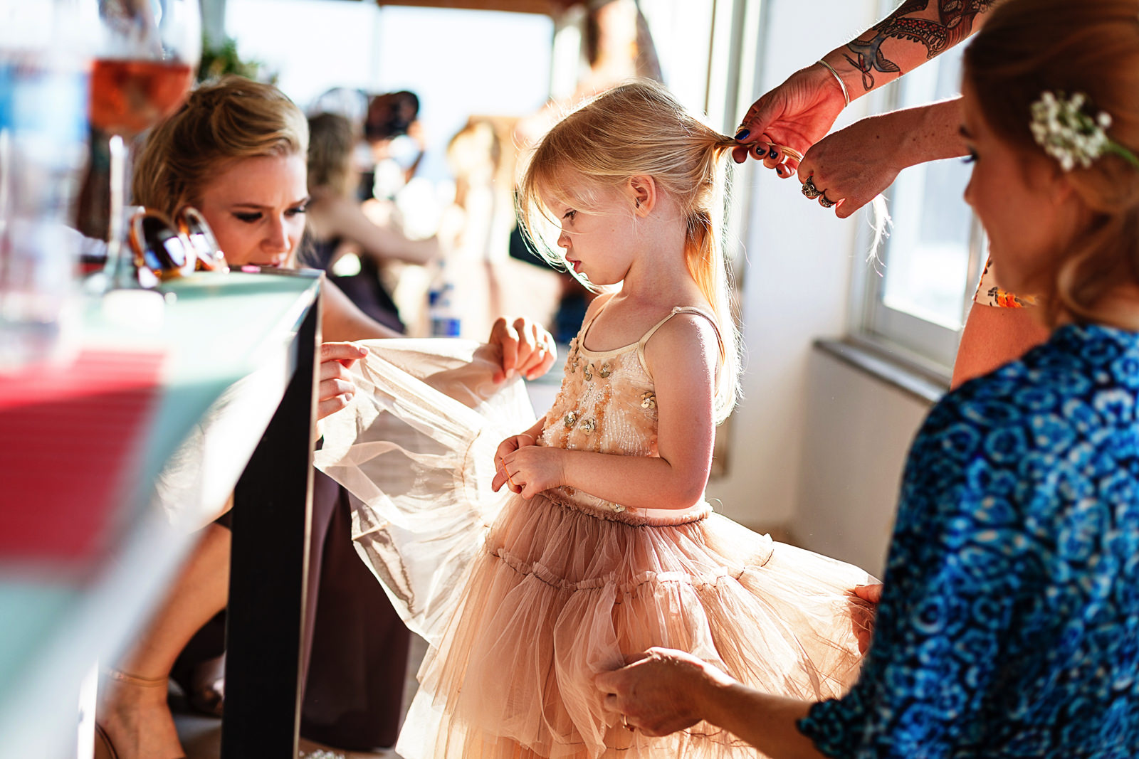 Bride and sister helping a toddler girl with hair and dress