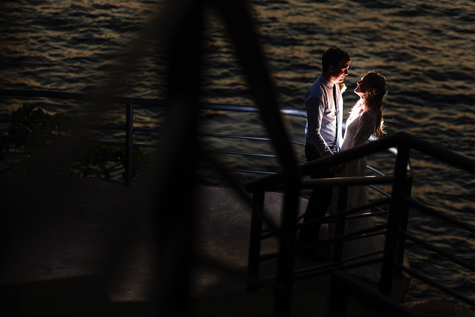 Groom and bride creative portrait against the pacific ocean in Puerto Vallarta, through the hand rails