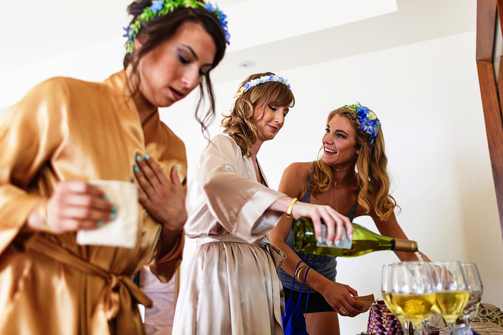 Bride serving champagne into a glass during the make-up and hair preparations in the bridal suite before the destination wedding ceremony