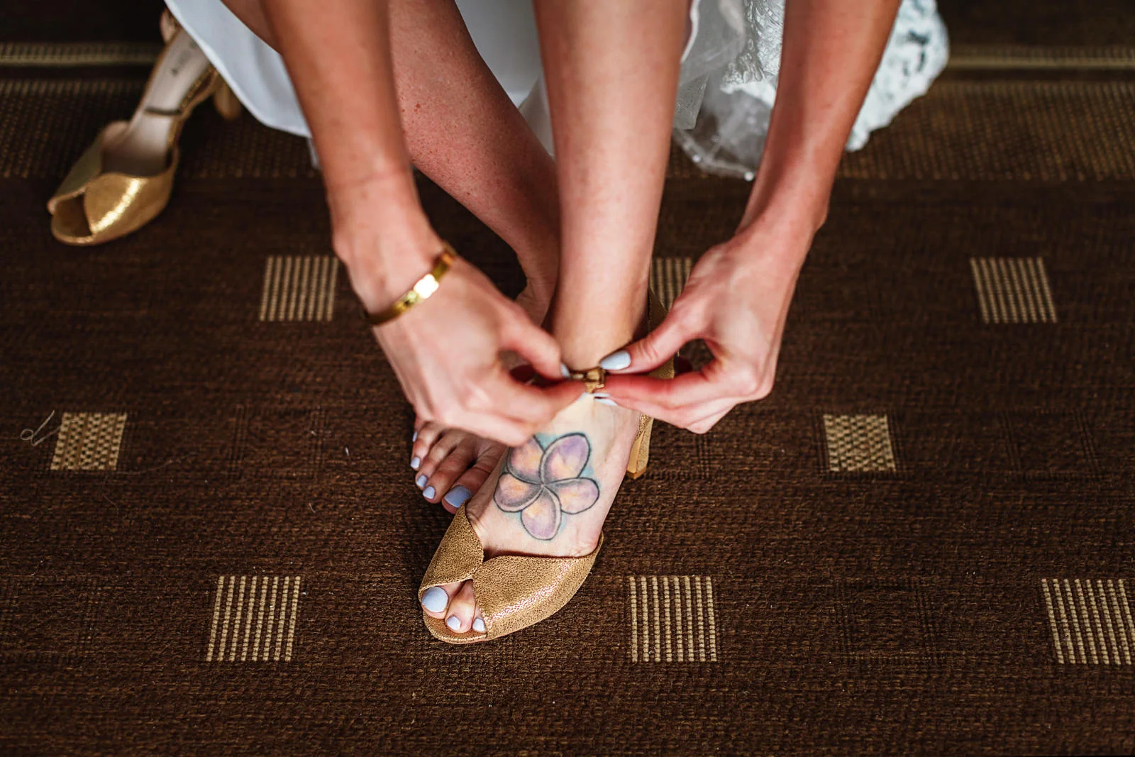 Bride putting her shoes on, a flower tatto on her left foot can be seen