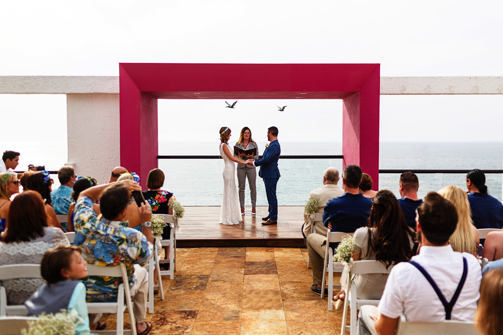 Two pelicans pass by on the background as the wedding ceremony beggins