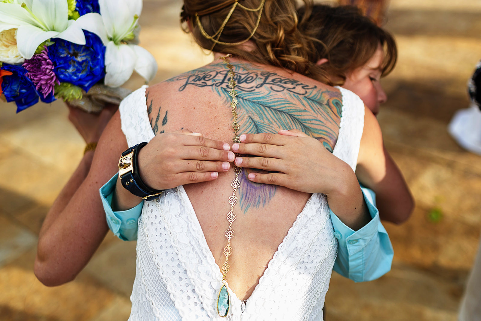 A kid hugs the bride and her back tatto can be seen