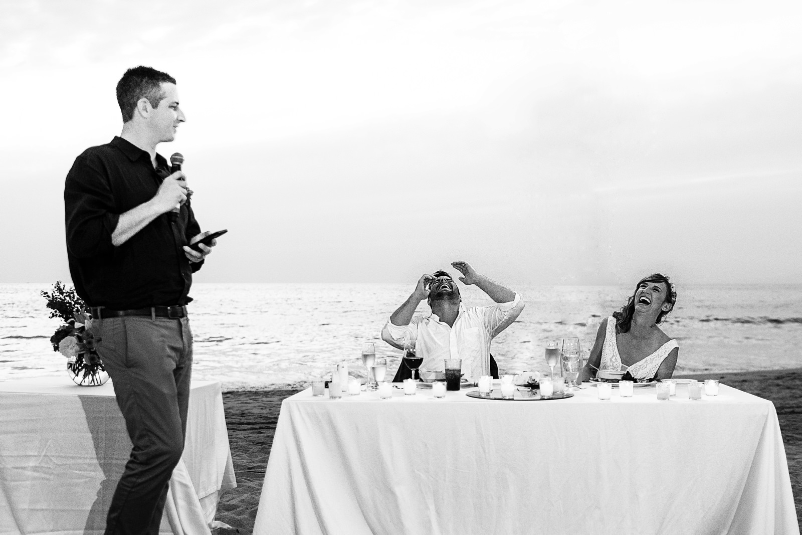 Bride and groom laugh during best man's speech