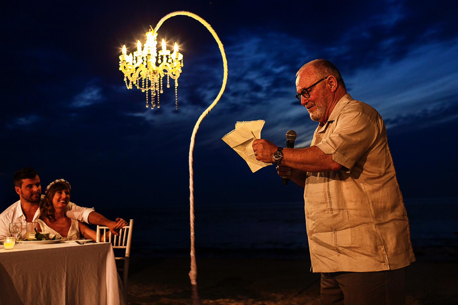 Father of the groom giving a speech to the couple as the night falls