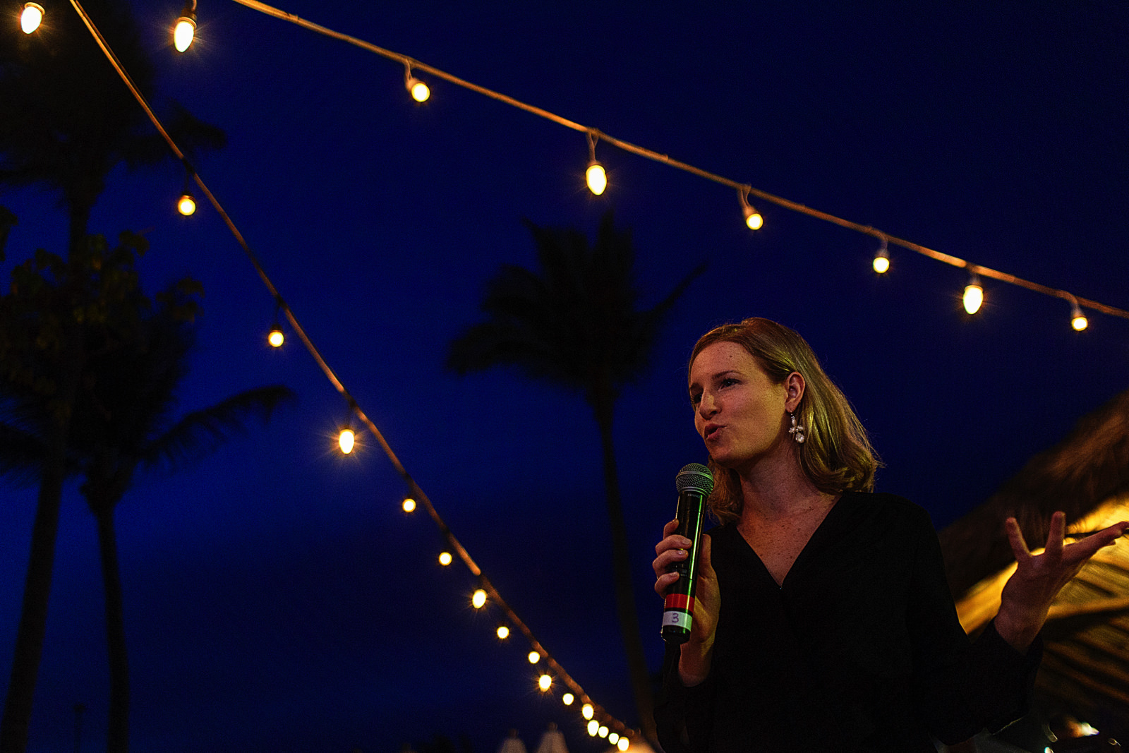 Wedding female guest giving a speech between yellow lights against the blue sky.