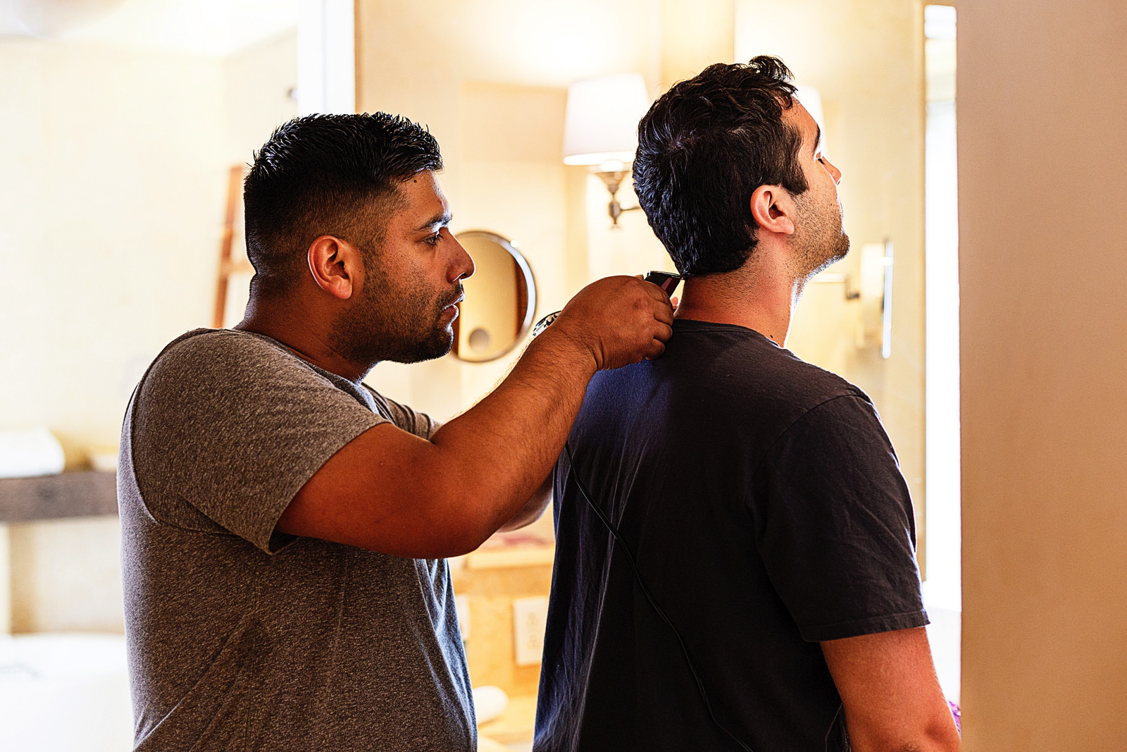 Groomsmen trimming the neck hair of the groom.