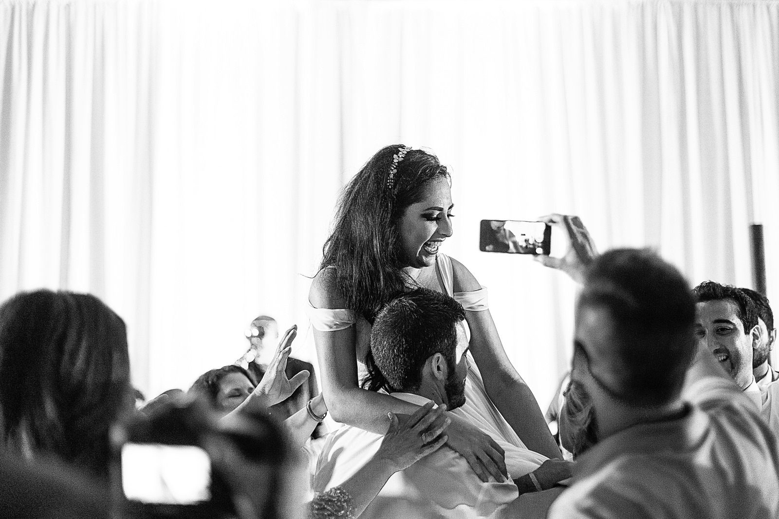 Bride is being lifted by friends in the dance floor during the wedding reception.