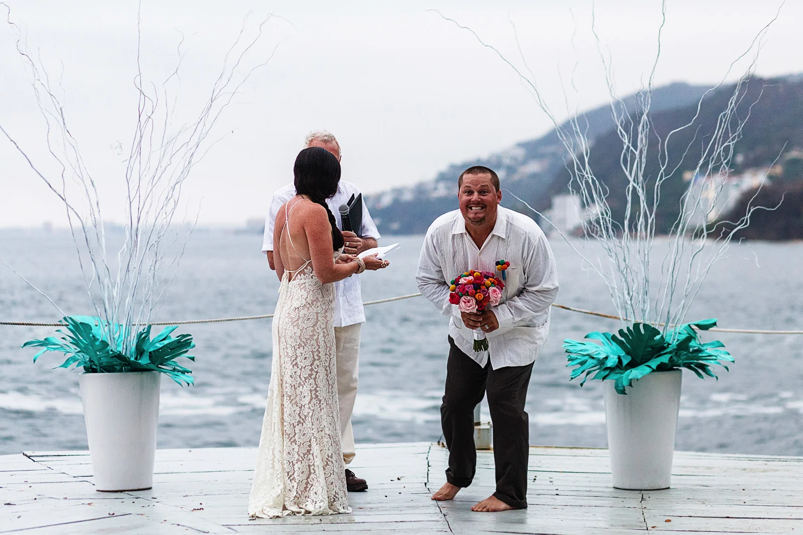 Groom takes the bouquet and smiles at the wedding guests as he turns to them